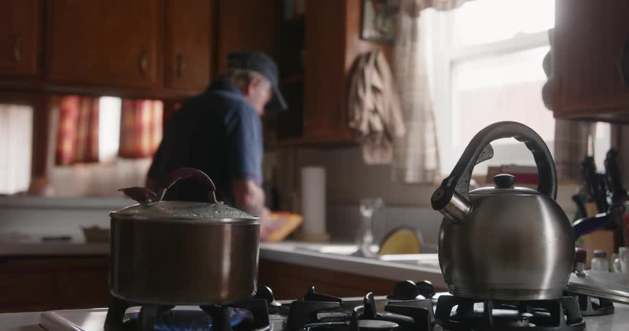 A man opens a package as he cooks in the kitchen