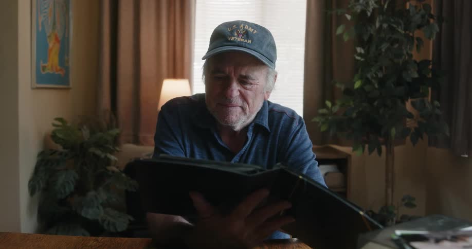 Elderly man with a blue cap and t shirt looks at photo album