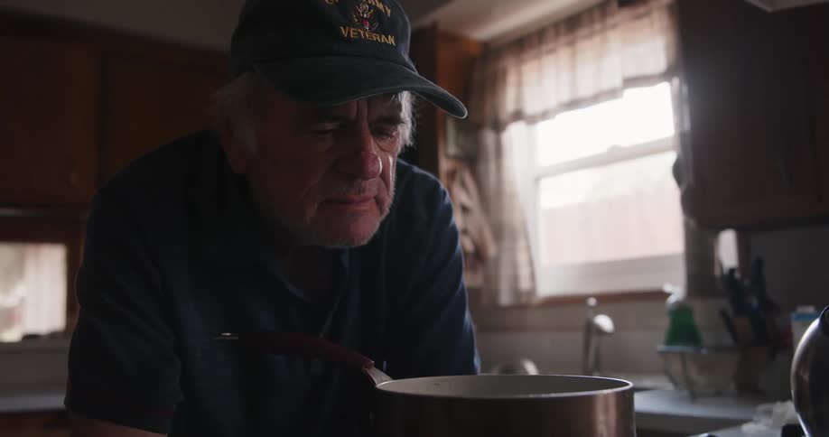 A man is watching a pot of food cook