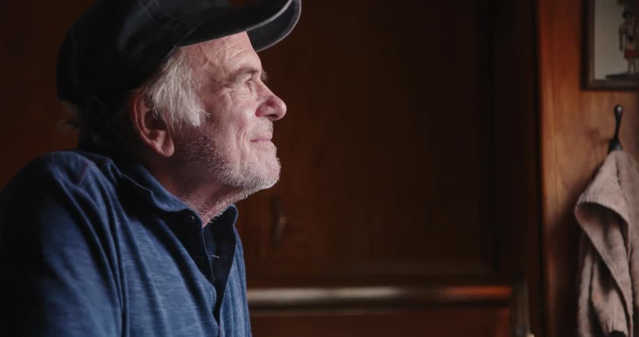 A man indoor smiling while deep in thought