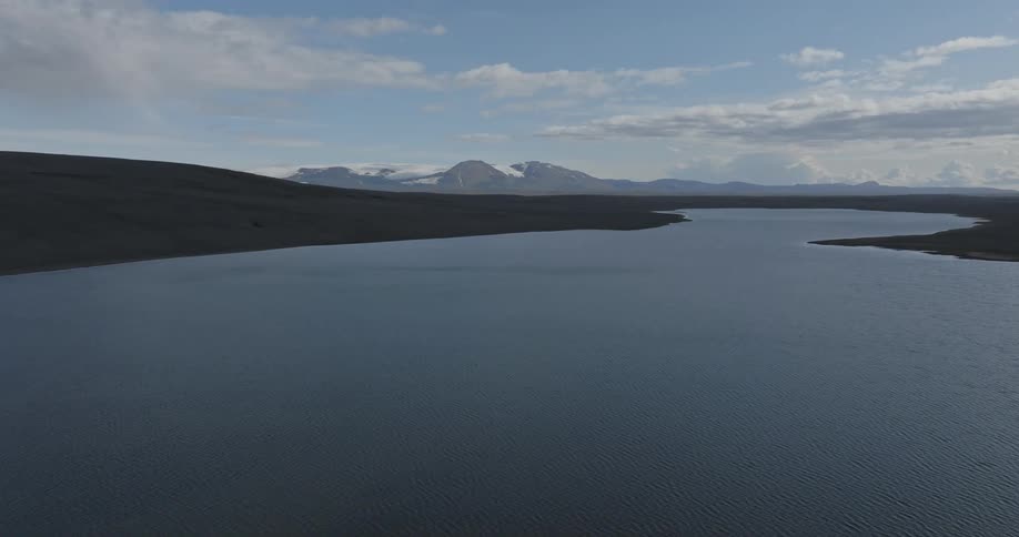 A lake is shown with smooth water and mountains around it