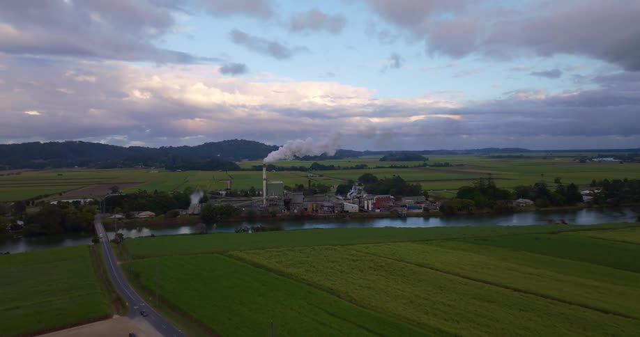 Aerial view of a rural area with a factory in the background by the riverside