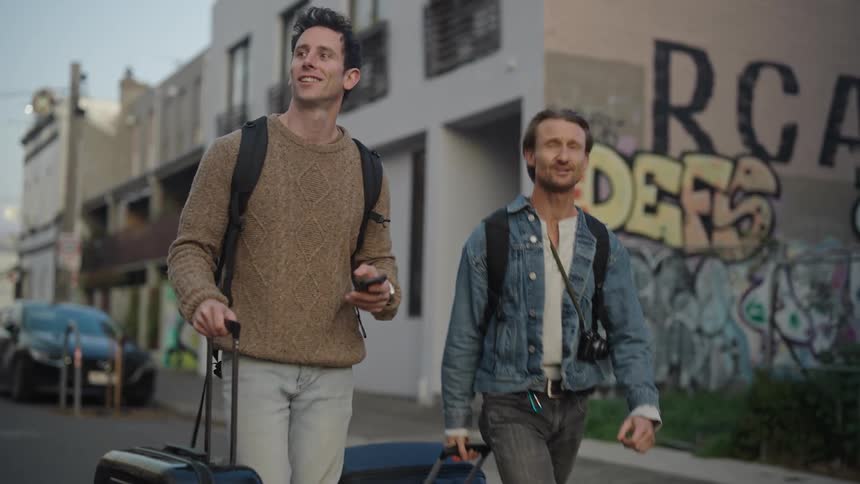 Two traveling men walking on the street at sunset
