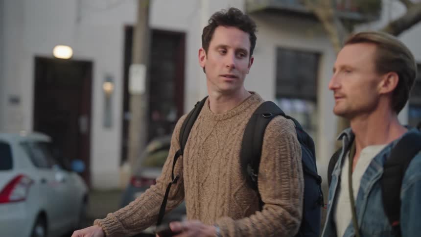 Two men walking in the city while conversing and smiling