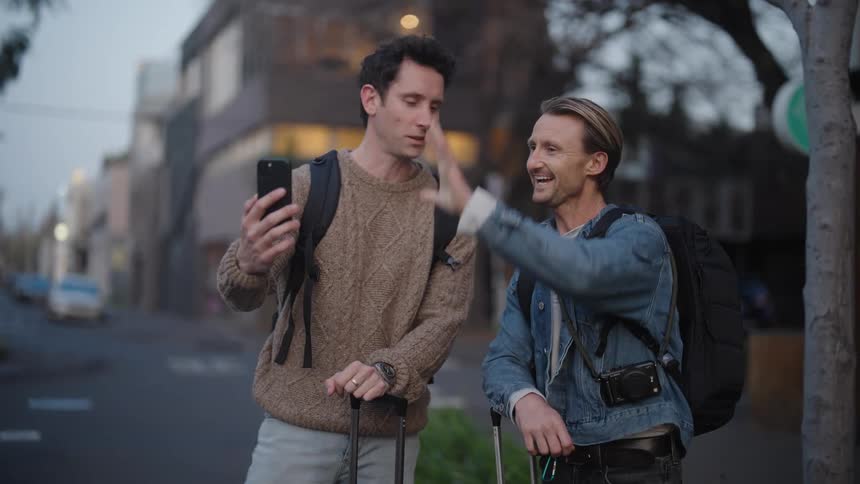 Two happy tourists have a video call while standing on streets of a town