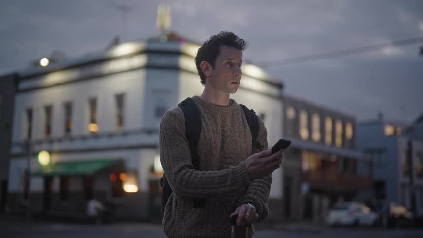 Man standing on the street looking at his cell phone