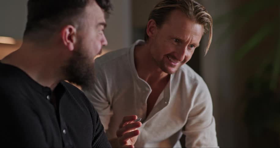 Two men looking at a laptop and looking at each other smiling at what they see