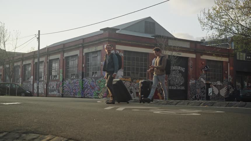 Two tourists carrying luggage wander around town