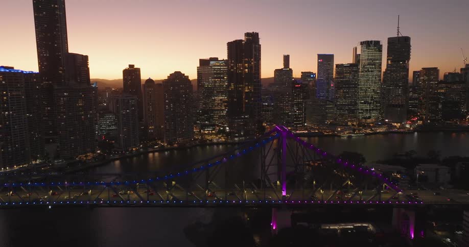 Aerial view of a metropolitan city by the sea with bridges during the early evening with a reddish sky
