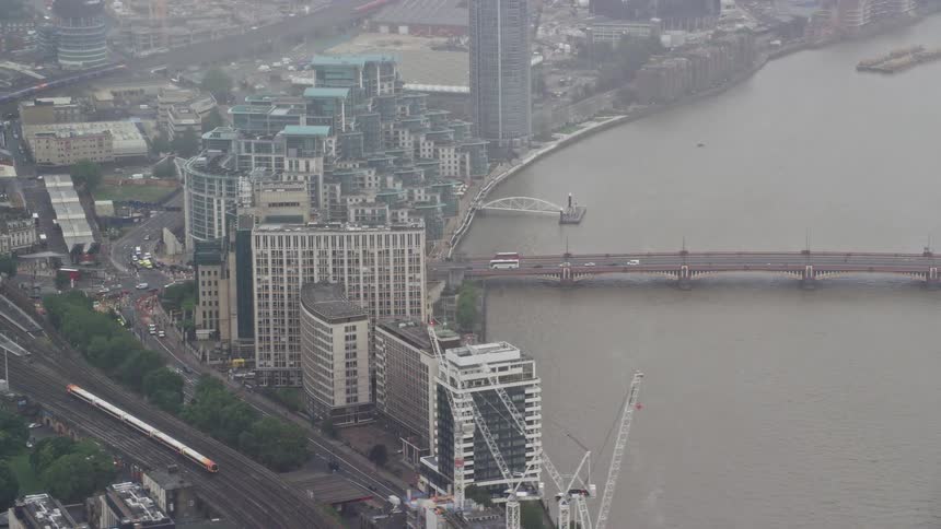 Aerial view of a city featuring a train track a bridge spanning a river within the urban area numerous skyscrapers and cars bustling along the roads