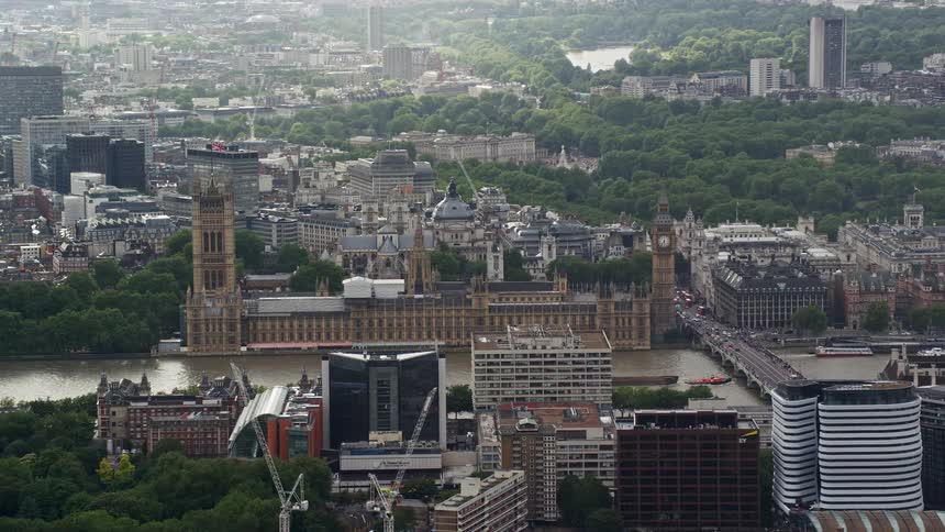 Tugboat pulls barge under bridge near the palace of westminster