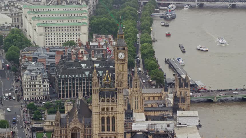 River and street traffic move past westminster palace across thames from ferris wheel