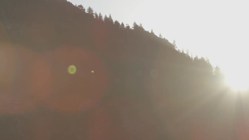 The sun is setting behind the trees on this mountain