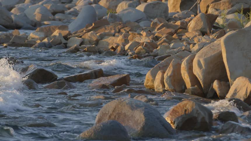 Waves breaking against boulders on a rocky shoreline