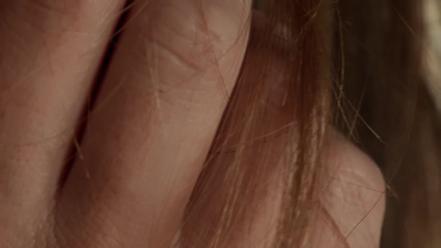A white woman is using her fingers to stretch her hairs downward