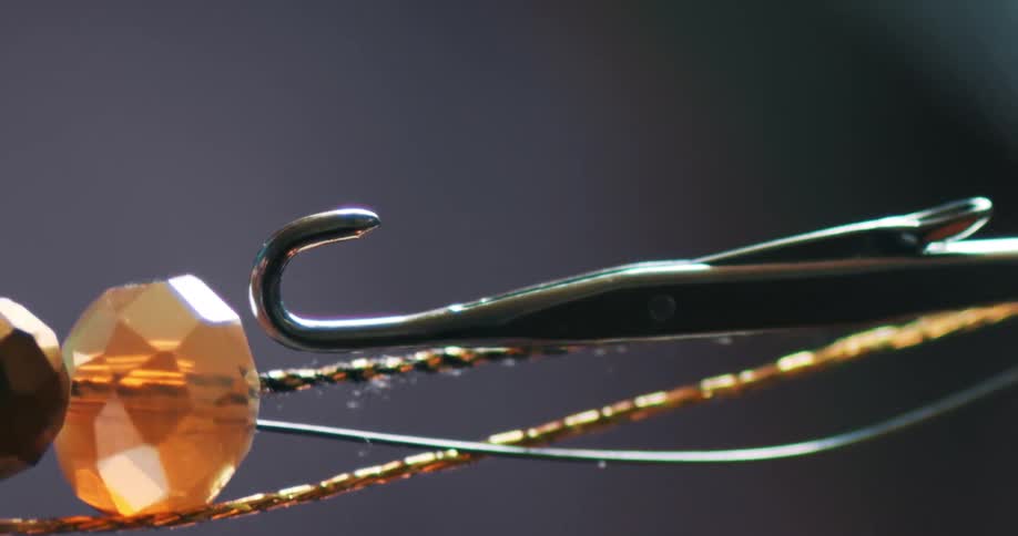 Close up of gemstones being threaded on a hook