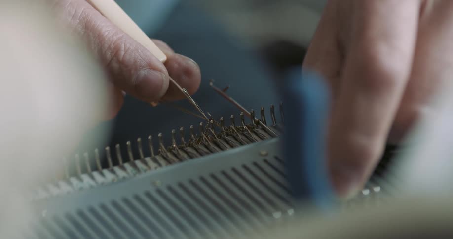Person using a tool on strings at midday