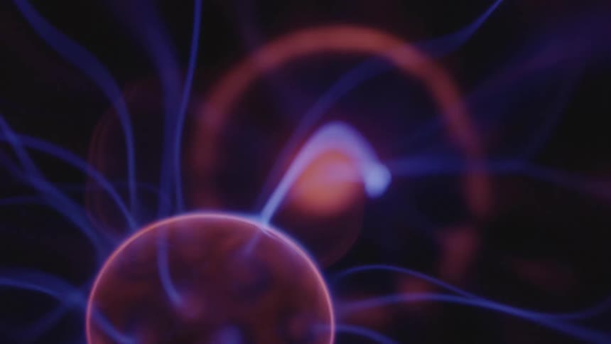 Glowing blue appendages extend from a luminous pink globe as it rotates and there is a glowing orb in the distance