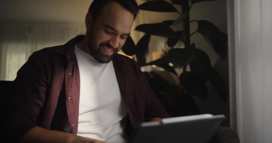 A man working on a tablet in the armchair at home