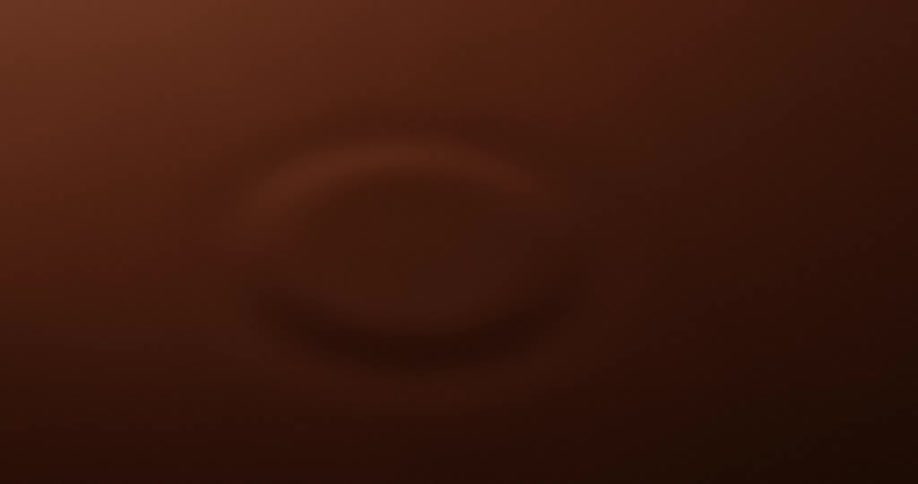 Drop of water falling into brown liquid