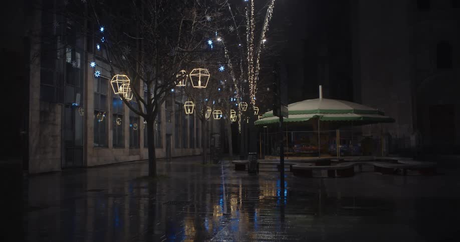 A city street on a rainy night decorated with christmas lights