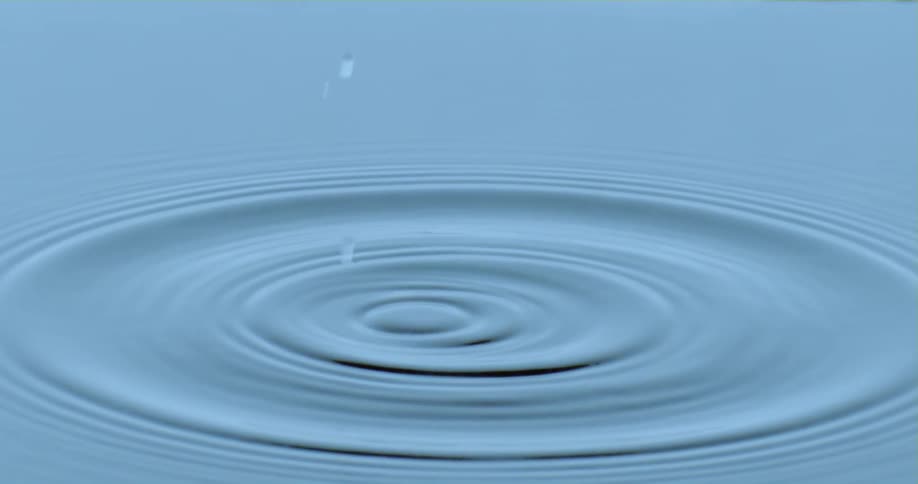 Droplet of water falling into abstract water and creating an impact