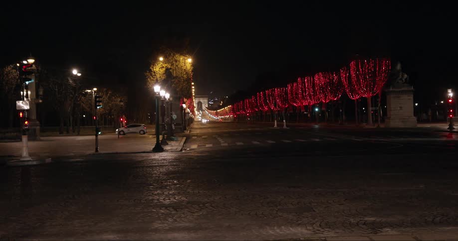 Vehicle drives along road intersecting decorated road leading to the arc de triomphe at night in paris