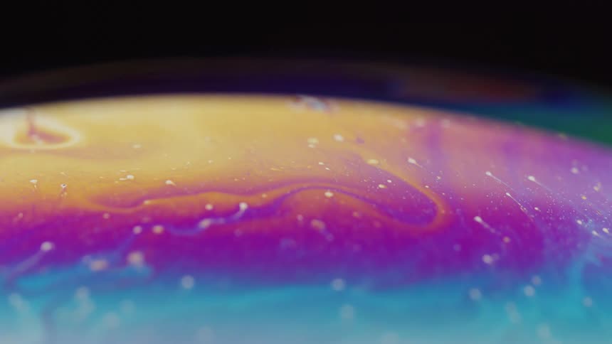 White dots move with fluorescent colors and stripes as they swirl on the surface of a sphere