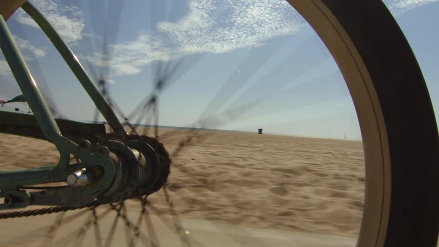 Close up of a bicycle wheel spinning near a beach