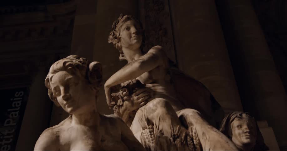 Classical marble sculpture of three women on a dimly lit setting