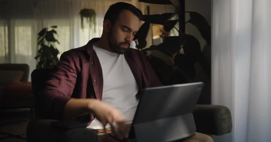 A frustrated man working on a computer indoor at midday