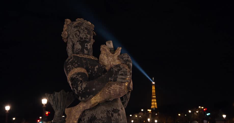 A statue of someone from a religious background holding a fish in a park surrounded by lots of light