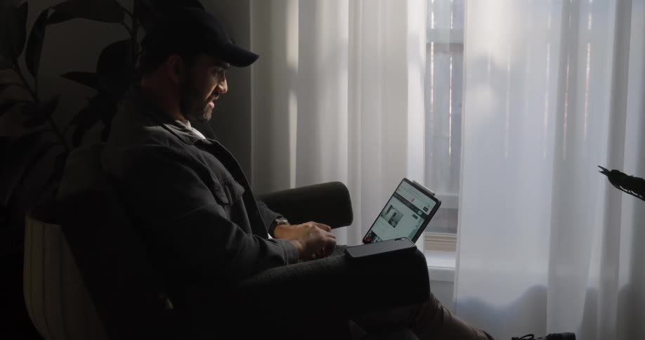A man sitting in an armchair working on the computer