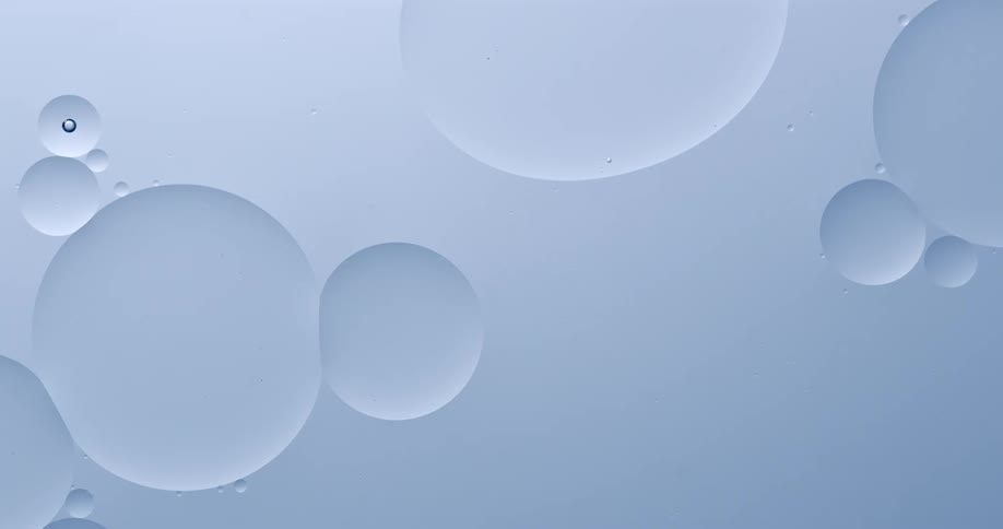 Oily bubbles float and blend on another blue liquid