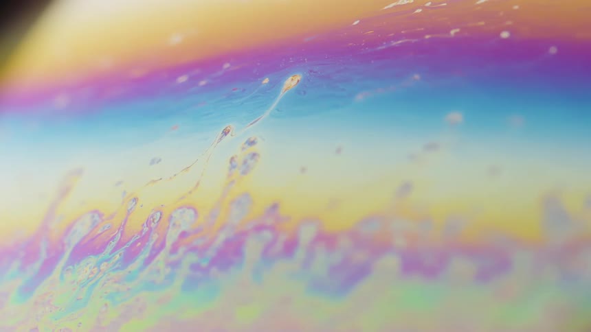 Orange purple and blue liquid spinning and bits of the colors are moving upward through the sections of color