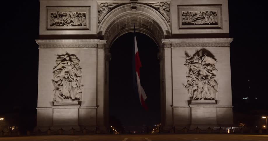 A monument with a hanging french flag at night