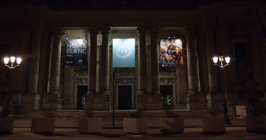The camera slowly zooms in on an urban museum facade lit up at night
