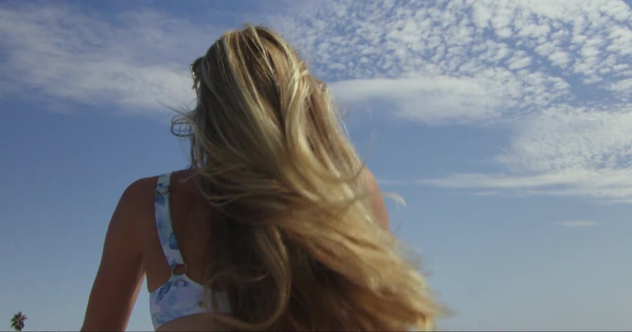 A blonde woman tosses her hair around on a windy day