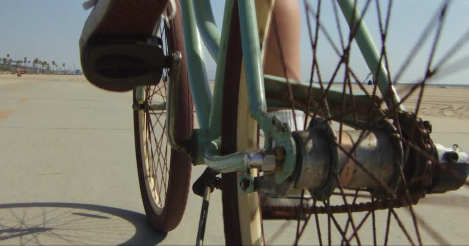 Cyclist pedals along road past beach