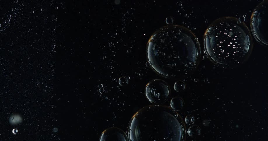 Various sized bubbles floating in black water