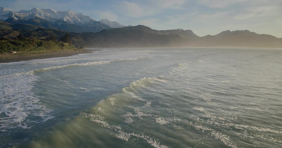 Ocean waves approach land with mountains