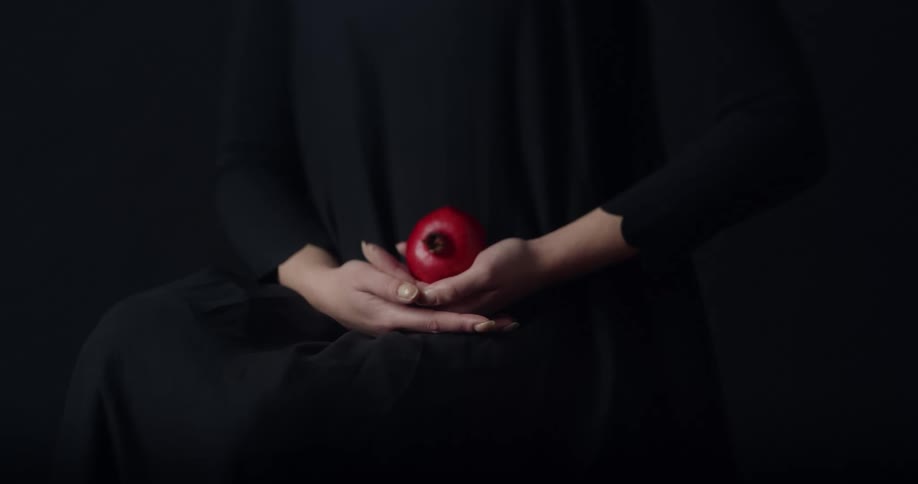 A person wearing black holding an apple