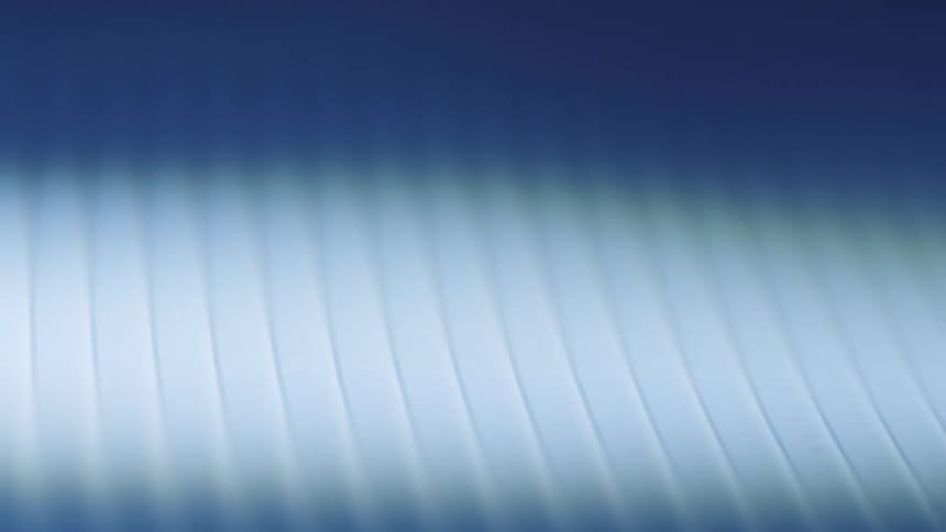 Spotlight moving across ribbed surface brightens then darkens