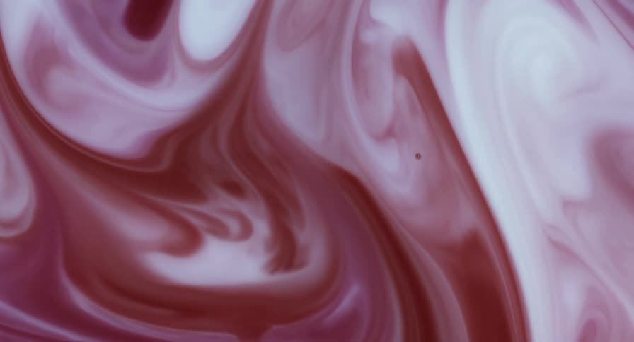 Maroon and white liquid swirls and mixes as it turns