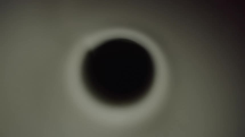 A black hole with little lighting remaining completely in the dark with the light fading