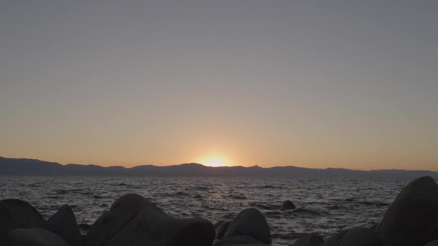 The sun is setting beyond the rough waters
