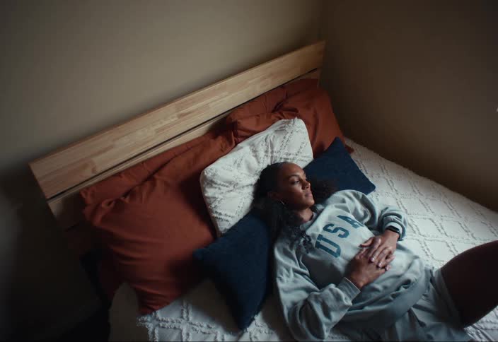 A woman looks out the window in a bedroom