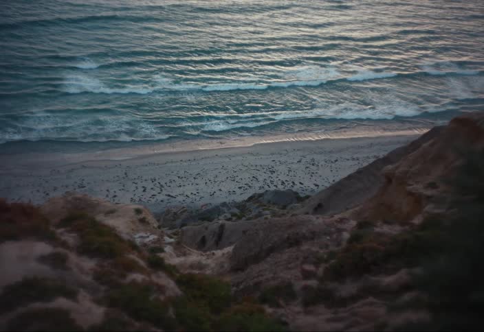 Shoreline of a beach next to the ocean seen from a cliff