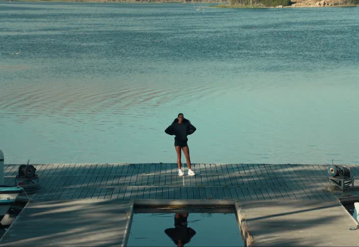 Woman stands on the dock at a lake