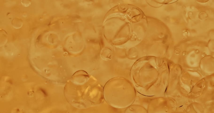 Transparent bubbles float through peach fluid